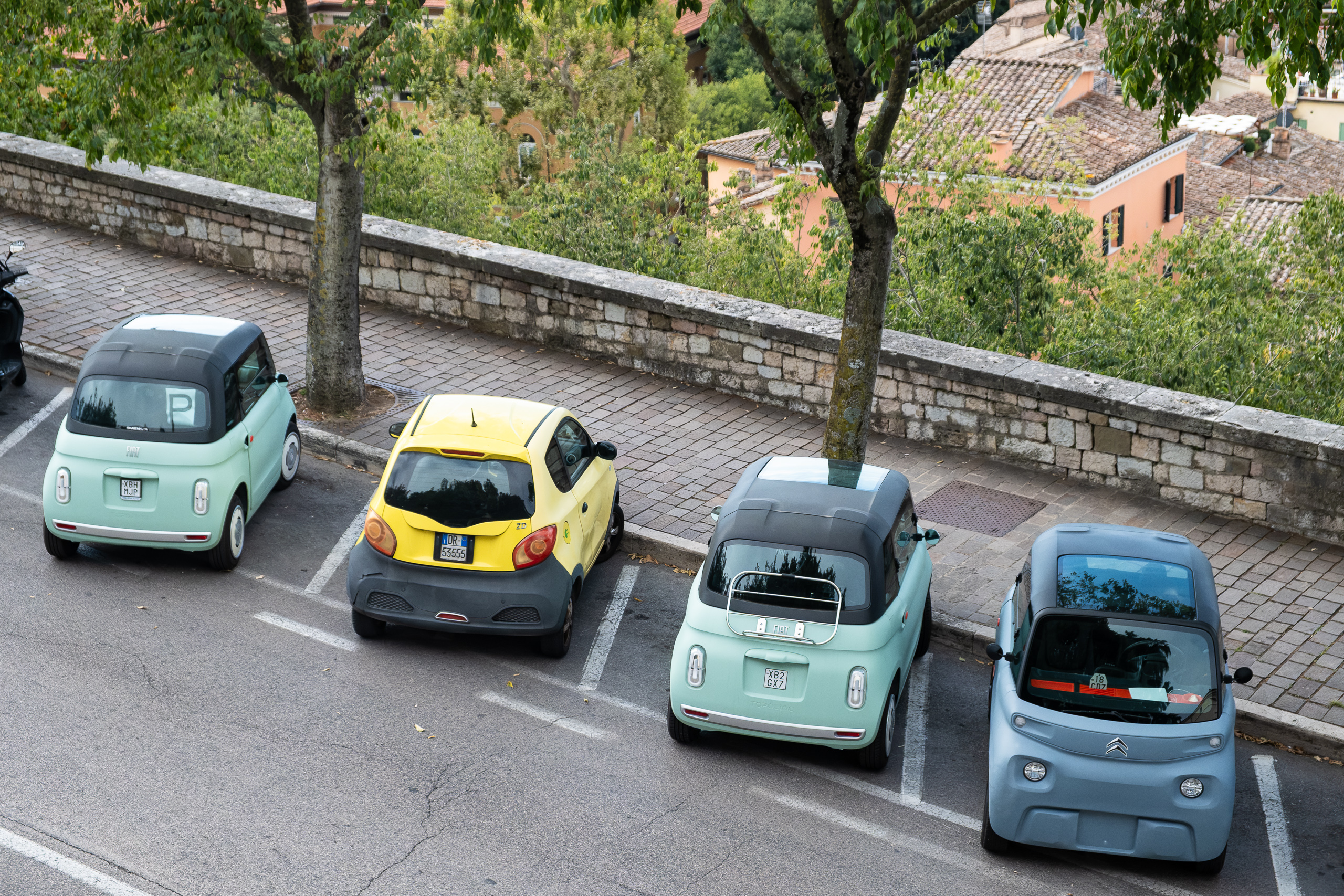 Elektro-Kleinwagen in Reih und Glied an der Stadtmauer